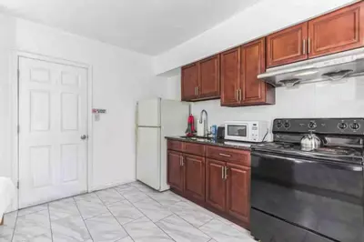 a kitchen with wooden cabinets and a black appliances at Spring Garden Small and Cozy Studio Sleeps 4 in Philadelphia