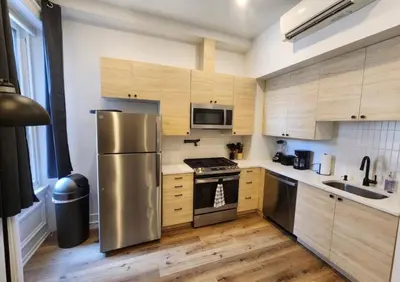 a kitchen with a stainless steel refrigerator and wooden cabinets at Renovated Jr 1BR - Center City - Sleeps 4 - 2 Beds in Philadelphia