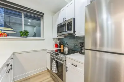 a kitchen with white cabinets and a stainless steel refrigerator at New 2BR Across from Fairmount Park - 10 mins to DT in Philadelphia