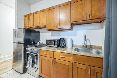 a kitchen with wooden cabinets and a stainless steel refrigerator at Quaint and Cozy Center City 1BR that Sleeps 4 in Philadelphia