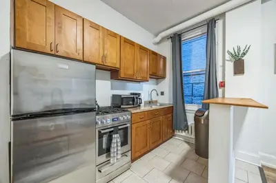 a kitchen with wooden cabinets and a stainless steel refrigerator at Quaint and Cozy Center City 1BR that Sleeps 4 in Philadelphia