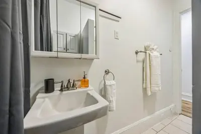 a white bathroom with a sink and a mirror at Quaint and Cozy Center City 1BR that Sleeps 4 in Philadelphia