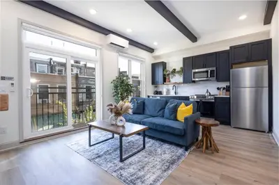 a living room with a blue couch and a kitchen at 1BR Across from Fairmount Park - 10 mins to DT (E) in Philadelphia