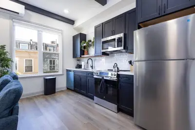 a kitchen with black cabinets and a stainless steel refrigerator at 1BR Across from Fairmount Park - 10 mins to DT (E) in Philadelphia