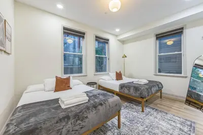a bedroom with two beds and a bench and windows at New 2BR Across from Fairmount Park - 10 Mins to DT in Philadelphia