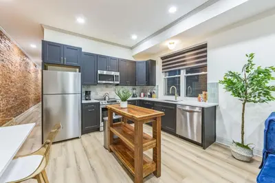a kitchen with black cabinets and a wooden table at New 2BR Across from Fairmount Park - 10 Mins to DT in Philadelphia