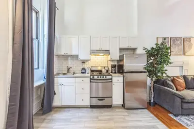 a kitchen with a stainless steel refrigerator and a couch at Large Historical Center City 1BR that Sleeps 4 in Philadelphia