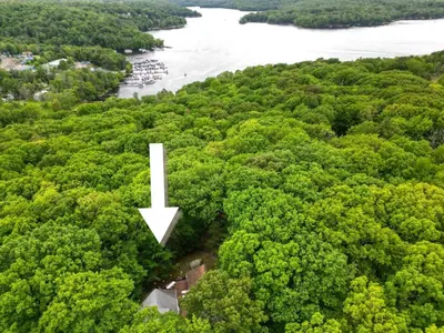an aerial view of a river and trees with a white arrow at 1mi to Lake Wallenpaupack | Firepit | Pet Friendly in Greentown