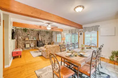 a living room with a table and chairs and a stone wall at 1mi to Lake Wallenpaupack | Firepit | Pet Friendly in Greentown