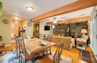 a dining room and living room with a stone wall at 1mi to Lake Wallenpaupack | Firepit | Pet Friendly in Greentown