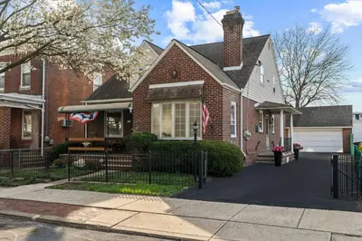 a red brick house with a flag on the front at Historic Tacony Retreat with Sauna in Philadelphia