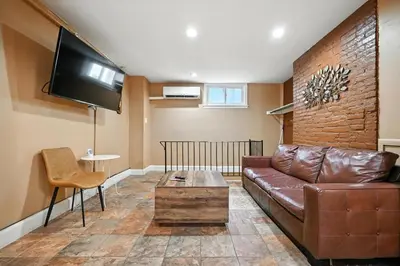 a living room with a brown leather couch and a tv at Charming Home in Vibrant Philadelphia in Philadelphia