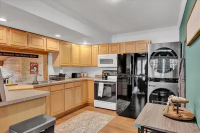 a kitchen with wooden cabinets and a black refrigerator at Tranquil Trails Cottage Fire Pit Cozy 3BDR in Gouldsboro