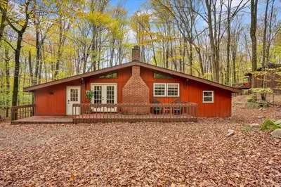 a small red house in the middle of a forest at Tranquil Trails Cottage Fire Pit Cozy 3BDR in Gouldsboro