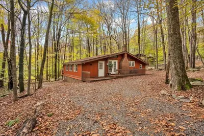 a small red cabin in the woods with trees at Tranquil Trails Cottage Fire Pit Cozy 3BDR in Gouldsboro