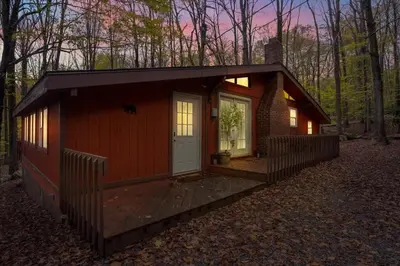 a small cabin with a porch in the woods at Tranquil Trails Cottage Fire Pit Cozy 3BDR in Gouldsboro