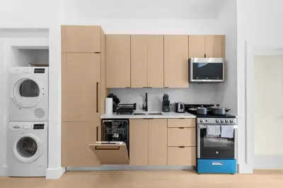 a kitchen with brown cabinets and a washer and dryer at 19-5D 2BR 2Baths Luxury Apt East Village in New York