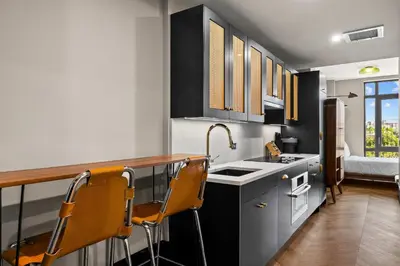 a kitchen with black and white cabinets and orange chairs at Freeman 603 by Rove Travel - Studio with Shared Amenities in New York