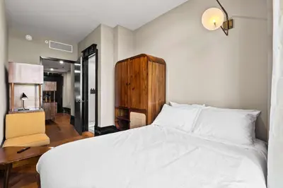 a bedroom with a white bed with a desk and a chair at Freeman II by Rove 1BR Condo with Shared Amenities in New York