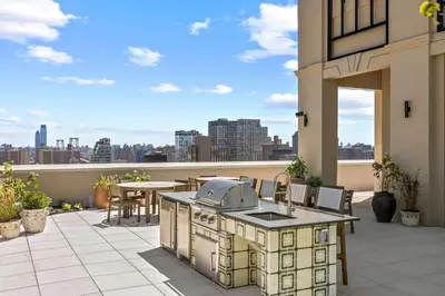 an outdoor kitchen on a patio with a view of the city at Freeman II by Rove 1BR Condo with Shared Amenities in New York
