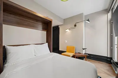 a bedroom with a white bed and a yellow chair at Freeman 201 by Rove Travel - 2BR Condo with Shared Amenities in New York