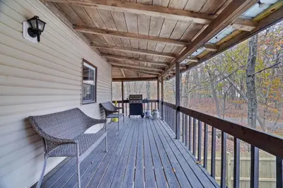 a porch with a bench and a grill on it at Winter retreat, hot tub, game room, indoor pool, in Long Pond