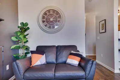 a leather couch in a living room with a clock on the wall at Mountain Chalet Ski, Hike, & Explore in Tannersville