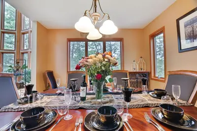 a dining room with a table with a vase of flowers at Harmony Haven Large Deck Hot Tub Ski in Split Rock