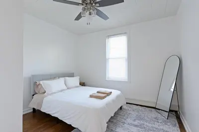 a white bedroom with a bed and a mirror at 20 min to NYC, Newly Renovated, Private Driveway in Little Ferry