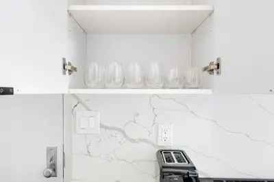 two pictures of a kitchen with glasses on a wall at Blueground Alphabet City view nr Tompkins Square Park NYC-1978 in New York
