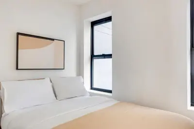 a white bedroom with a bed and a window at Blueground Alphabet City view nr Tompkins Square Park NYC-1978 in New York