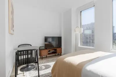 a bedroom with a bed and a desk and a tv at Blueground Alphabet City rooftop nr Tompkins Square Park NYC-2081 in New York