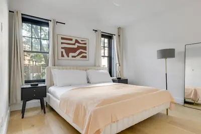a white bedroom with a bed and two windows at Blueground Brooklyn Heights view nr Brooklyn Bridge NYC-1987 in Brooklyn
