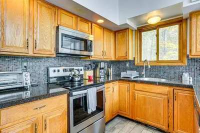 a kitchen with wooden cabinets and stainless steel appliances at Luxury Home with Game Room, 4 Mi to Bushkill Falls! in Saw Creek