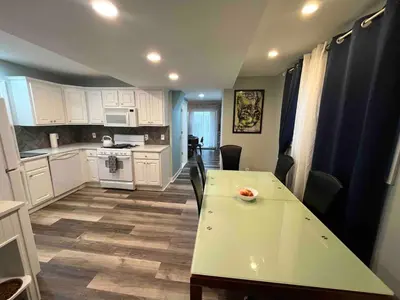 a kitchen with white cabinets and a table with chairs at Odessa in Keansburg