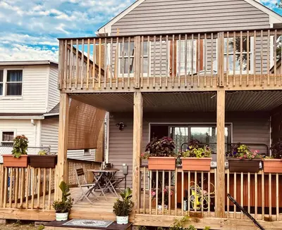 a wooden house with potted plants on a deck at Odessa in Keansburg