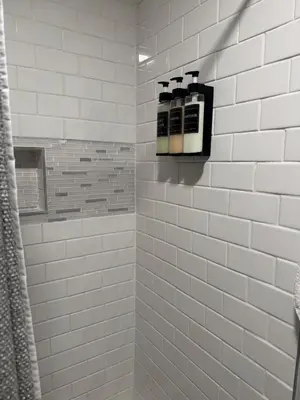 a white tiled shower with two soap dispensers at Modern Stay in Downtown Jersey City, Close to NYC! in Jersey City