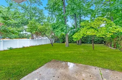 a yard with trees and a white fence at Peaceful 3BR House w Easy NYC Access in South River, NJ in South River