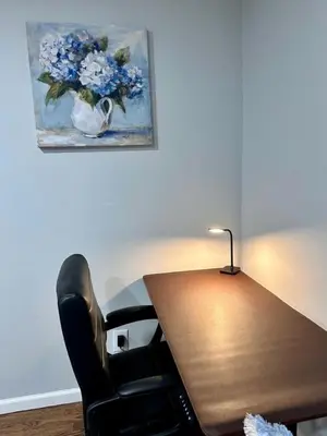 a desk with a chair and a vase of flowers at Peaceful 3BR House w Easy NYC Access in South River, NJ in South River