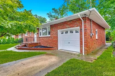 a red brick house with a white garage at Peaceful 3BR House w Easy NYC Access in South River, NJ in South River