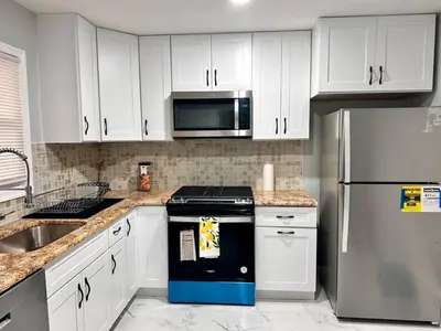 a kitchen with white cabinets and a stove and a refrigerator at Peaceful 3BR House w Easy NYC Access in South River, NJ in South River