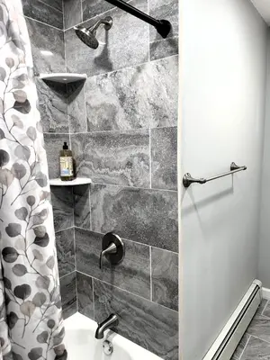a bathroom with a shower with a stone wall at Peaceful 3BR House w Easy NYC Access in South River, NJ in South River