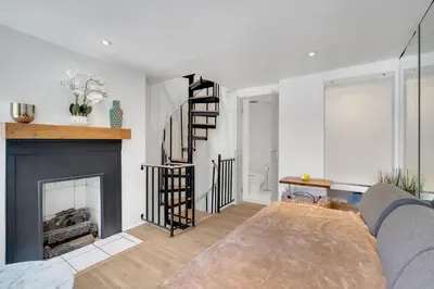 a living room with a fireplace and a staircase at The Twisty Nest on 17th in Philadelphia