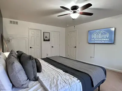 a bedroom with a bed with a ceiling fan at Pocolonial Charming 4BR Mountain Retreat in Albrightsville