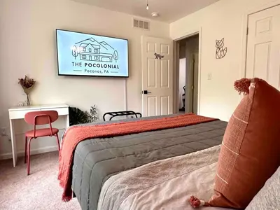 a bedroom with a bed and a tv on the wall at Pocolonial Charming 4BR Mountain Retreat in Albrightsville