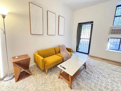 a living room with a yellow couch and a table at Residence Heritage Giant 3 Bedroom in New York