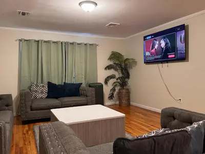 a living room with a couch and a tv on the wall at Urban haven 3 Kings bedroom near EWRNYC DTW in Newark