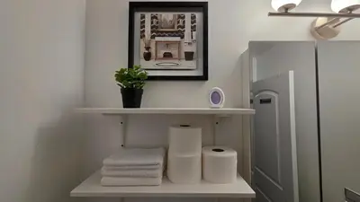 a bathroom with a shelf with towels and a mirror at Work & Stay - NYC - EWR - Train Walk in Newark