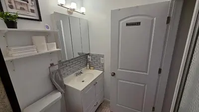 a white bathroom with a sink and a mirror at Work & Stay - NYC - EWR - Train Walk in Newark