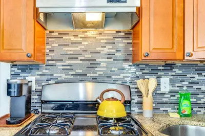 a yellow tea kettle sitting on top of a stove in a kitchen at Quiet Newark Apt Near Colleges, Arenas and Hospitals in Newark